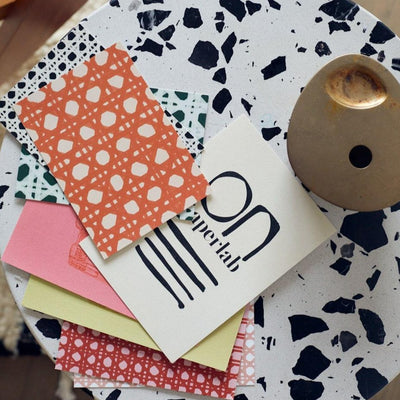 Colorful postcards flatlay on a black and white terrazzo table.